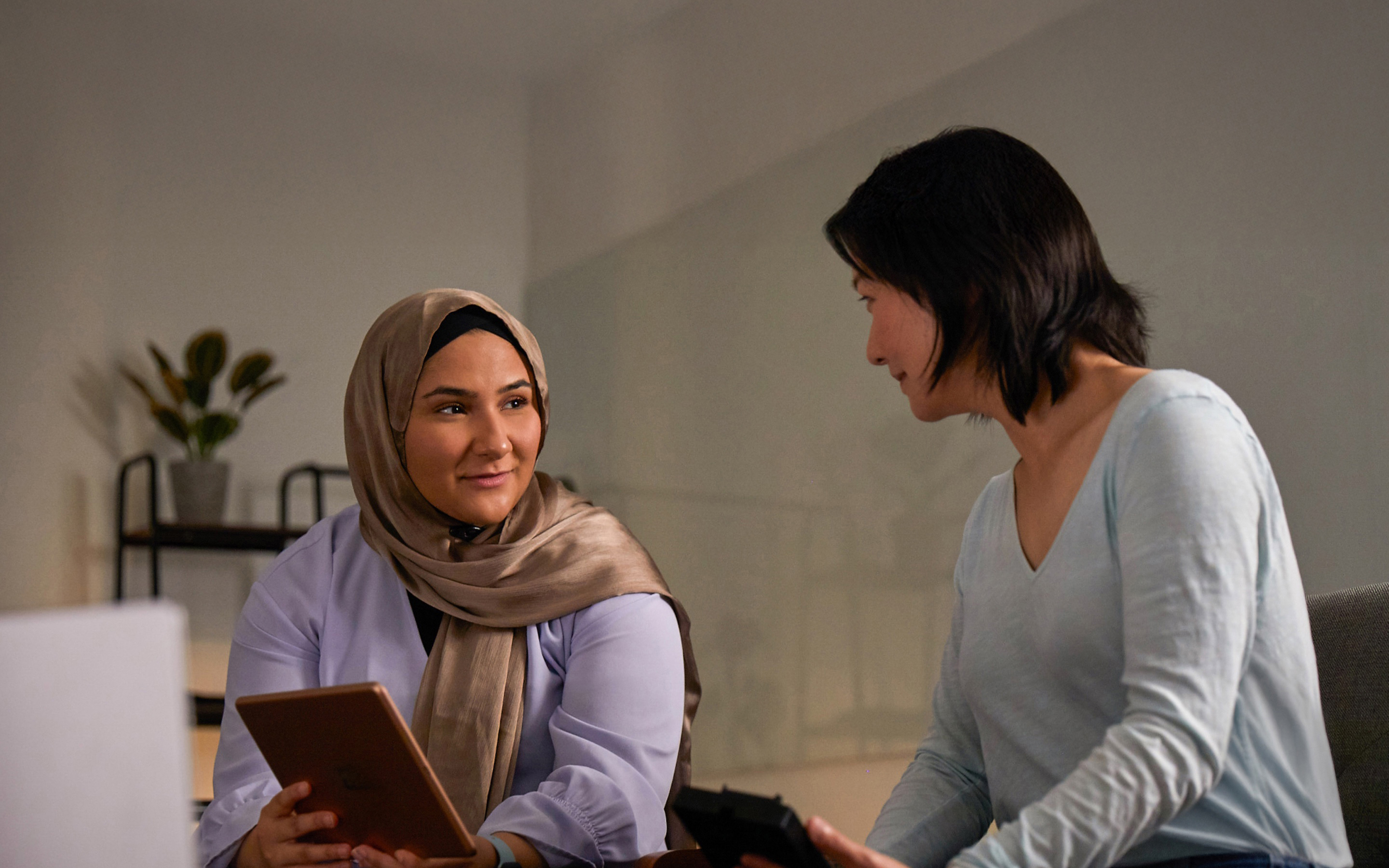 Dos personas del equipo de IA y aprendizaje automático de Apple colaboran, una de ellas con un iPad y la otra con un iPhone.