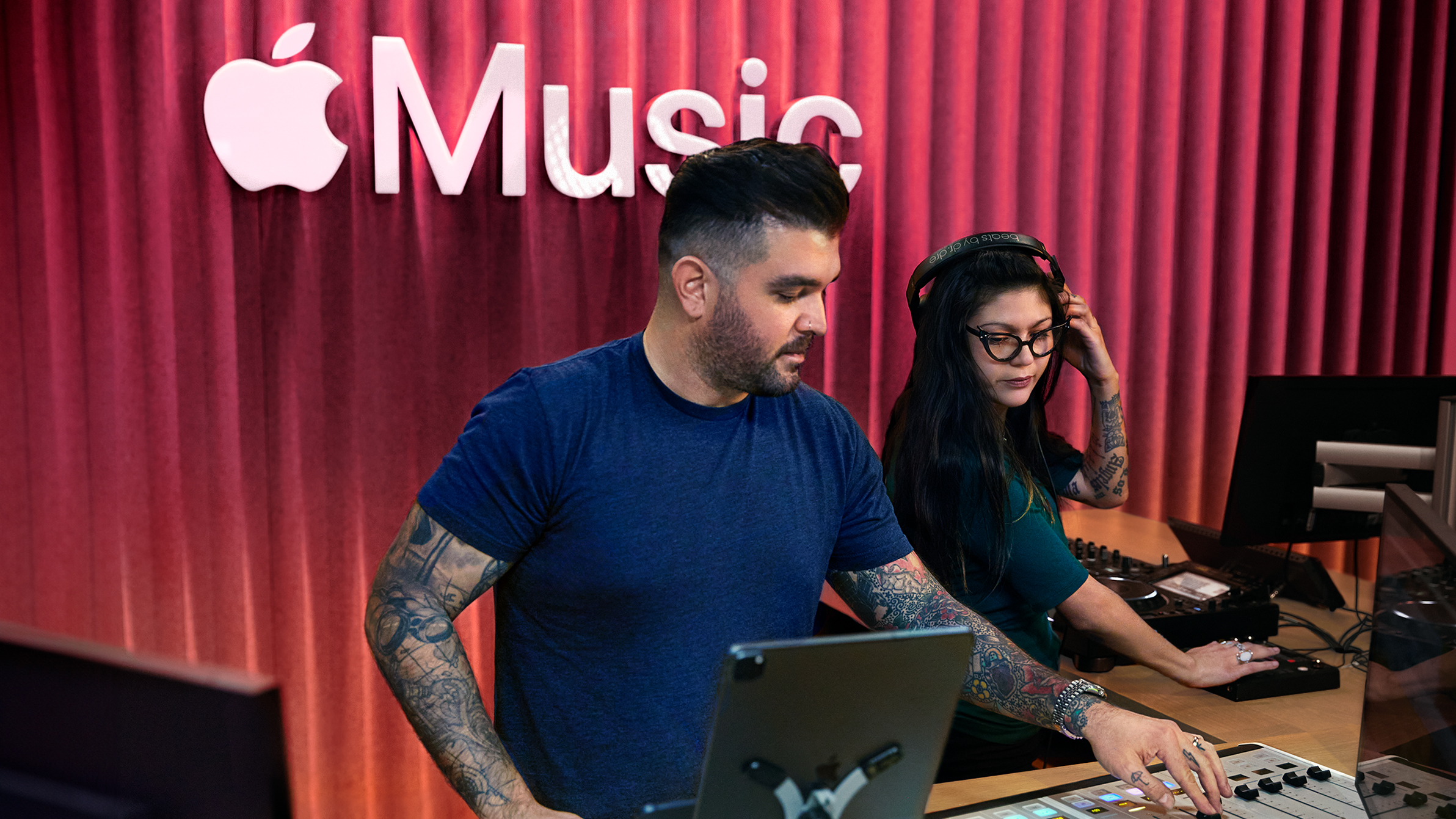 Twee Apple medewerkers achter een audiomengpaneel in een Apple Music-studio.
