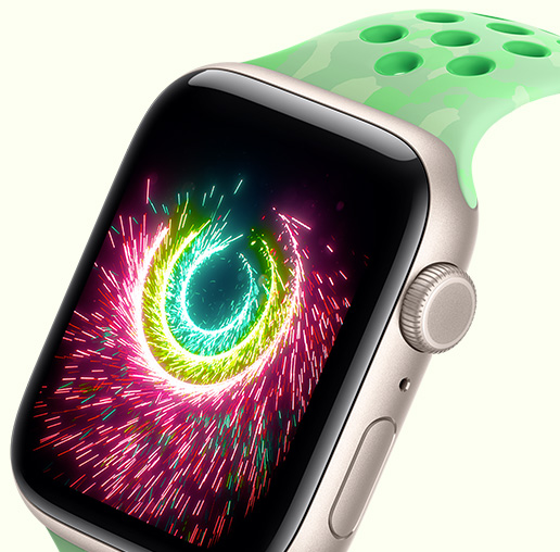 Apple Watch SE 3, la pantalla muestra los anillos de Actividad que emiten destellos como fuegos artificiales, caja de aluminio, color blanco estrella, con correa Nike Sport, color verde destello (verde menta, diseño discreto de formas grises, perforaciones circulares)