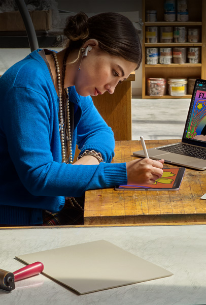 Uma estudante sentada à mesa desenha no iPad com o Apple Pencil