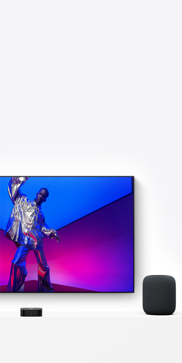 Apple TV 4K og HomePod i farven midnat, TV-skærmen viser en kunstner i et metallisk sølvfarvet outfit
