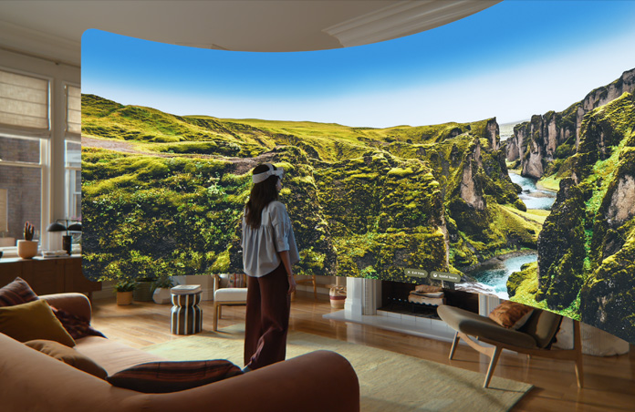 Vue d’un Apple Vision Pro, image panoramique de falaises rocheuses verdoyantes traversées par un ruisseau et surmontées d’un ciel bleu s’étendant à perte de vue