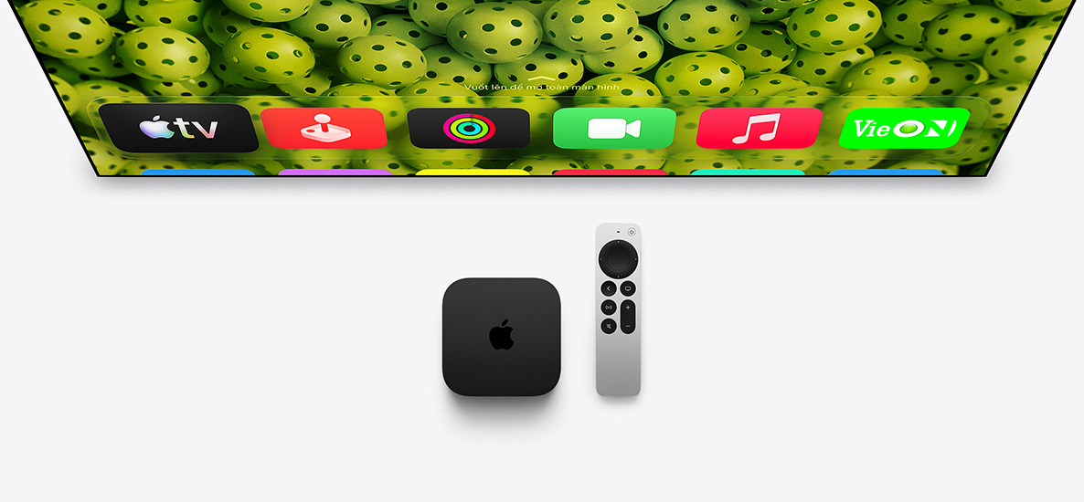 Apple TV 4K và Siri Remote phía dưới màn hình TV, màn hình hiển thị các biểu tượng ứng dụng ở hàng trên cùng của Màn Hình Chính, trên nền các quả bóng pickleball màu xanh lá cây
